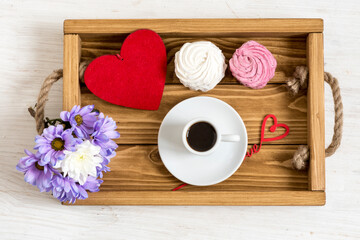 Morning cup of coffee with dessert for a lover. Top view of a tray with flowers and a drink