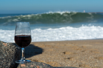 Tasting of different fortified dessert ruby, tawny port wines in glasses on sandy beach with view on waves of Atlantic ocean near Vila Nova de Gaia and city of Porto, Portugal