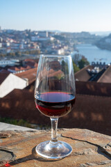 Tasting of different fortified dessert ruby, tawny port wines in glasses with view on Douro river, porto lodges of Vila Nova de Gaia and city of Porto, Portugal
