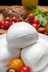 Cheese collection, white balls of soft Italian cheese mozzarella, served with red cherry tomatoes, fresh basil leaves