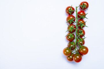 Vine of fresh ripe sweet cherry tomatoes ready to eat on white background