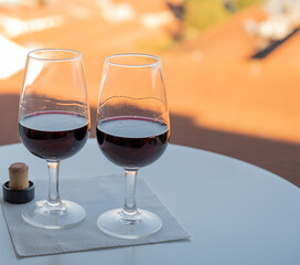 Tasting of different fortified dessert ruby, tawny port wines in glasses with view on Douro river, porto lodges of Vila Nova de Gaia and city of Porto, Portugal