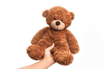 Hand of caucasian young man holding cute brown teddy bear doll over isolated white background