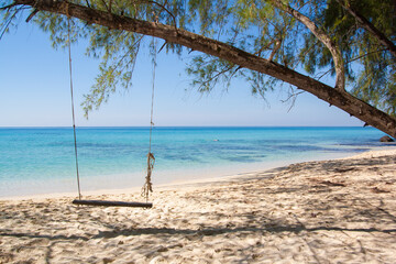 Tropical paradise beach of Thailand with white sand and turquoise waters and a swing hanging from a branch tree, vacation destination 