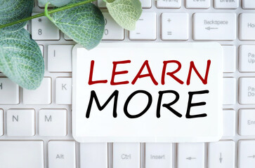 learn more, text on white paper on white keyboard