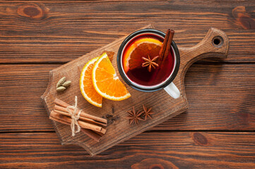 mulled wine in glass mugs with oranges and spices. new year decorations on the background. winter cozy warming drink on a wooden cutting board along with the ingredients. Preparation of a drink. view 