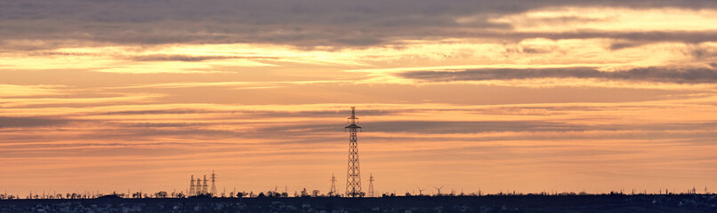 Power lines against the background of a yellow-orange multicolor sunset