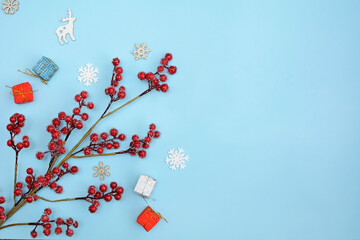 Layout of gift boxes, decorative branches with red berries and snowflakes on a blue background. Top view