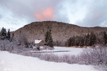 Sunrise view of the Jacques-Cartier National Park with its river and a small abandoned cabin seen during a winter blue hour morning, Stoneham-et-Tewkesbury, Quebec, Canada