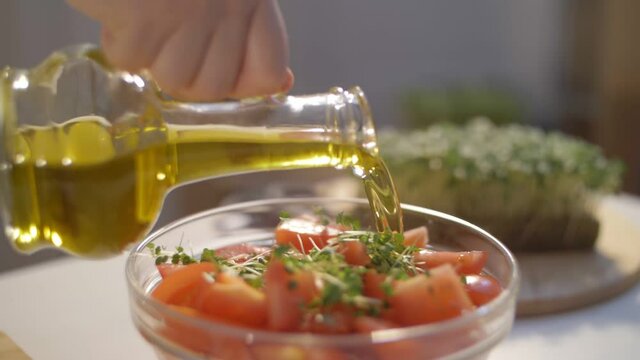 fresh tomato salad with microgreens and olive oil. olive oil pouring, organic vegetables, vegan diet. arugula micro greens. tomato harvest
