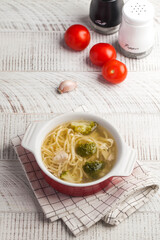 Homemade chicken soup with noodles and vegetables on a wooden table top.