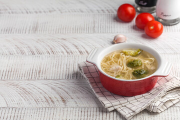 Homemade chicken soup with noodles and vegetables on a wooden table top. Copy space.