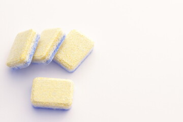Yellow blue dishwasher tablets, solid soap for washing machine, on white isolated close up, copy space