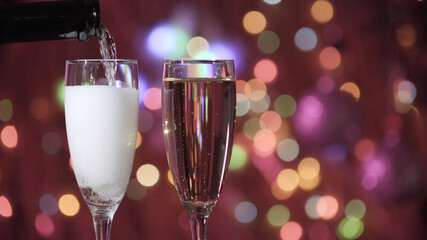 Champagne glass close up on Christmas and New Year holiday bokeh background. Two glasses with bubbly tasty sparkling drink. Happy New Year! Celebrating winter holidays, 4K, close up, macro