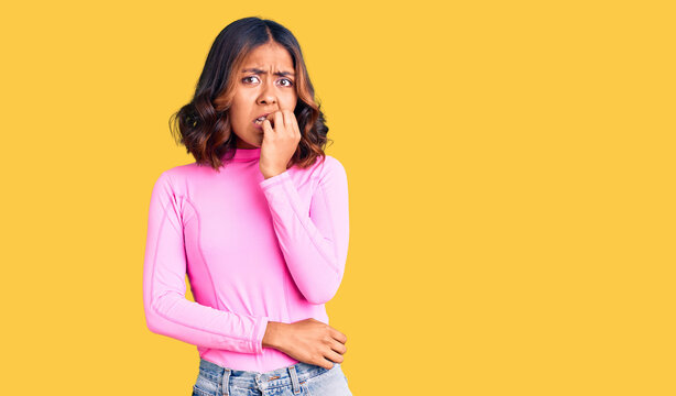 Young beautiful mixed race woman wearing pink shirt looking stressed and nervous with hands on mouth biting nails. anxiety problem.