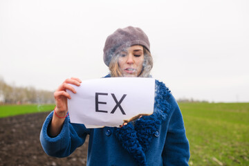 Conceptual portrait of sad girl hold burning smoldering white paper with printed word ex about...