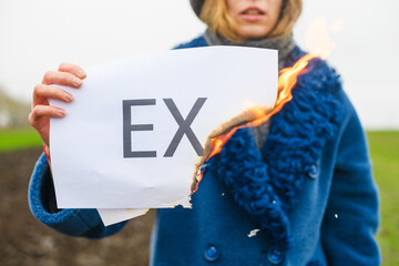 Close up white paper with printed word Ex in female hand outdoors, finished relations, divorce,...