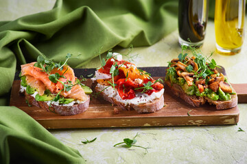Selection of tasty bruschetta or canapes on taosted baguette and quark cheese topped with smoked salmon, olives, tomato and chorizo sausage