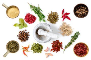 Various spice and herbs scattered on white background