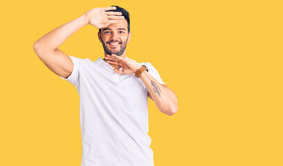 Young handsome hispanic man wearing casual clothes smiling cheerful playing peek a boo with hands showing face. surprised and exited