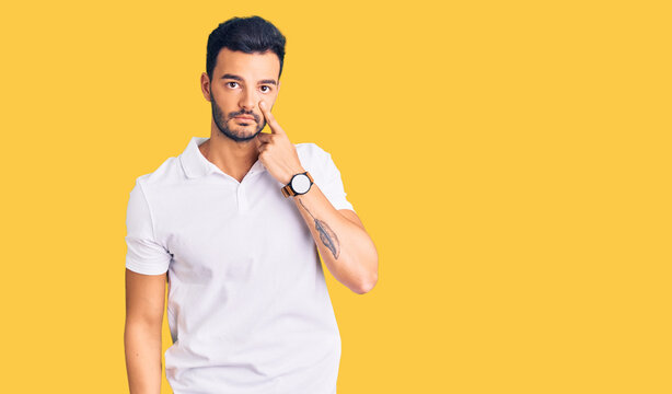 Young handsome hispanic man wearing casual clothes pointing to the eye watching you gesture, suspicious expression