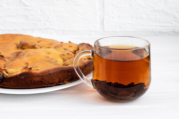 Apple pie rosy delicious on a white background on a white plate with tea
