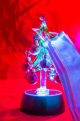 Mini Christmas tree wearing a blue facemask concept photo.