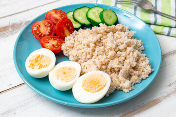 Healthy food, diet. Barley porridge, chicken eggs and vegetables on a wooden background.