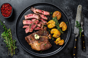 Cut Grilled rib eye beef meat steak with potato. Black background. Top view