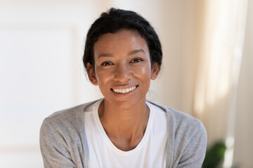 Close up headshot portrait of smiling young African American woman renter or tenant at home....