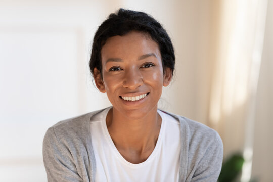 Close up headshot portrait of smiling young African American woman renter or tenant at home. Profile picture of happy millennial biracial 20s female have video call or webcam digital virtual talk.