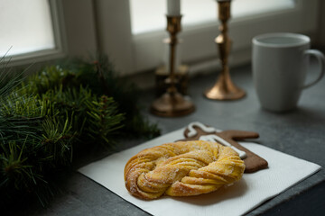 Cozy festive coffee break with christmas saffron bun and gingerbread. In the background is a coffee cup, candles and Christmas decoration. Photo taken in Sweden.
