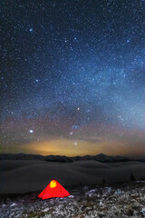Space starry nights with a bright Milky Way on the backdrop of tourists with tents.