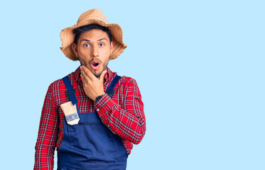 Handsome latin american young man weaing handyman uniform looking fascinated with disbelief, surprise and amazed expression with hands on chin