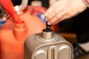 地震/台風/災害時の停電対策にもなる暖房器具「石油ストーブ/石油ファンヒーター」のタンンクに灯油を電動式ポンプで補給する女性の手元。電源不要 防災対策