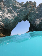 Underwater split photo of tropical exotic rocky arch in deep turquoise paradise sandy bay of Pacific island destination