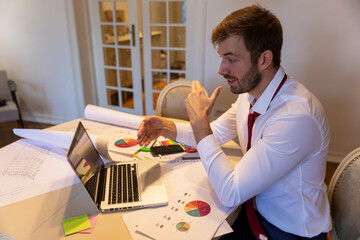 Young businessman is working remotely from home and having an online call on his laptop. 