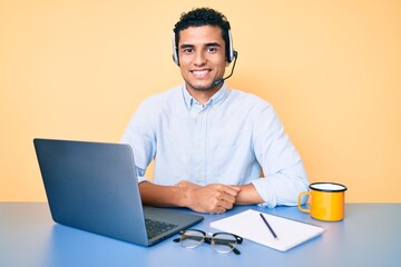 Young handsome hispanic man working at the office wearing operator headset with a happy and cool...