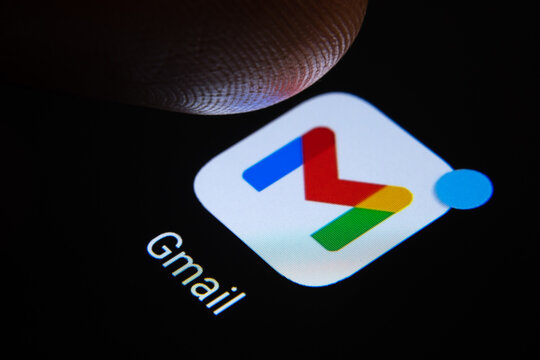 Google Gmail app with notification and blurred finger tip above it ready to press the screen. The new application look introduced in 2020. Stafford / United Kingdom - November 12 2020.