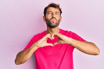 Handsome man with beard making heart symbol with hands shape looking at the camera blowing a kiss...