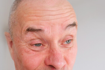 eyes, forehead of elderly man close-up, concept of restoration of human vision, health of optic nerve, nervous tic, myopia, hyperopia, vision test, anti-aging procedures, human emotions