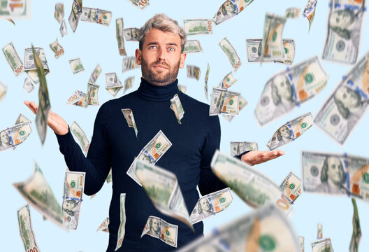 Young handsome blond man wearing casual turtleneck sweater clueless and confused expression with arms and hands raised. doubt concept.