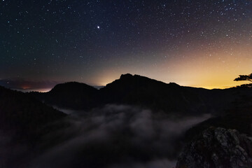 A beautiful starry night in the mountains on top with beautiful scenery and fog.	
