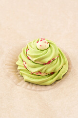 Round green meringue cake, close up on a light background