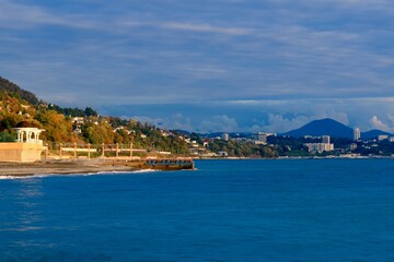 Obraz premium sea coast with a cape with a rotunda on a pebble beach against the backdrop of a mountain town