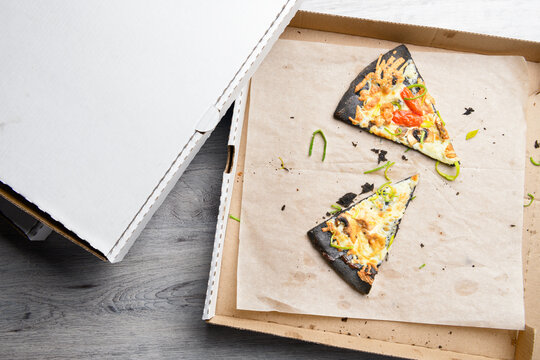 Used Opened Pizza Box With Two Pieces Of Eaten Pizza, Stains And Crumbs Inside On Table Background. Top View. Home Delivery And Stay Home Concept.