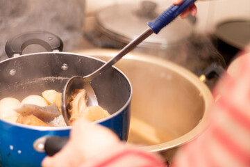 大量のあつあつのおでんを小さめの鍋に取り分ける。和食/大家族/日本の文化と食生活/冬の風物詩