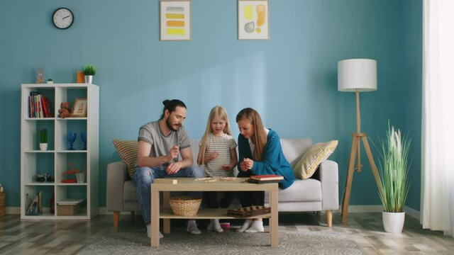 Young family stays home, having great leisure time, playing board game together, picking up sticks one by one and communicating, Slow motion.