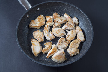 Chicken breast pieces in a pan made only with salt and white pepper on a dark ambient backdrop