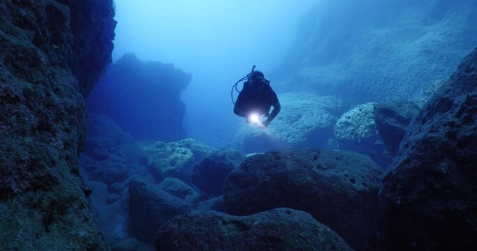 scuba divers exploring the reefs and underwater with rocks ocean scenery